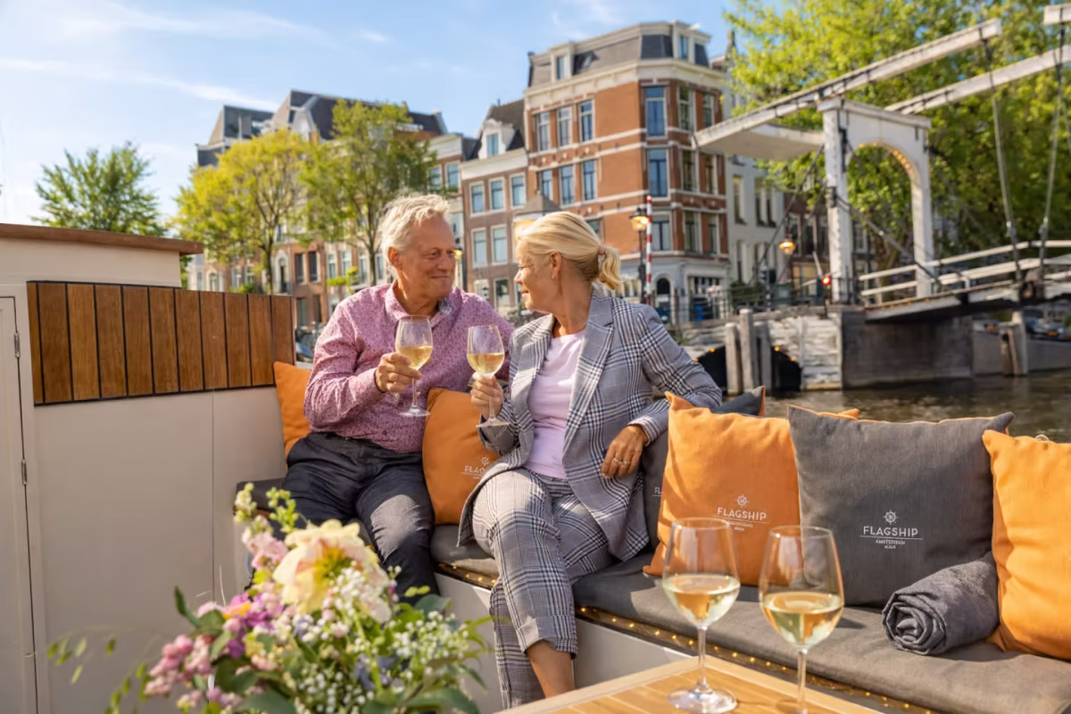 A couple enjoys wine together on a romantic Amsterdam canal cruise.
