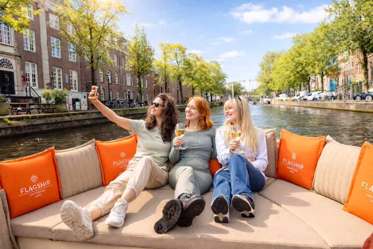 Three friends take a selfie and drink wine on an Amsterdam canal cruise.