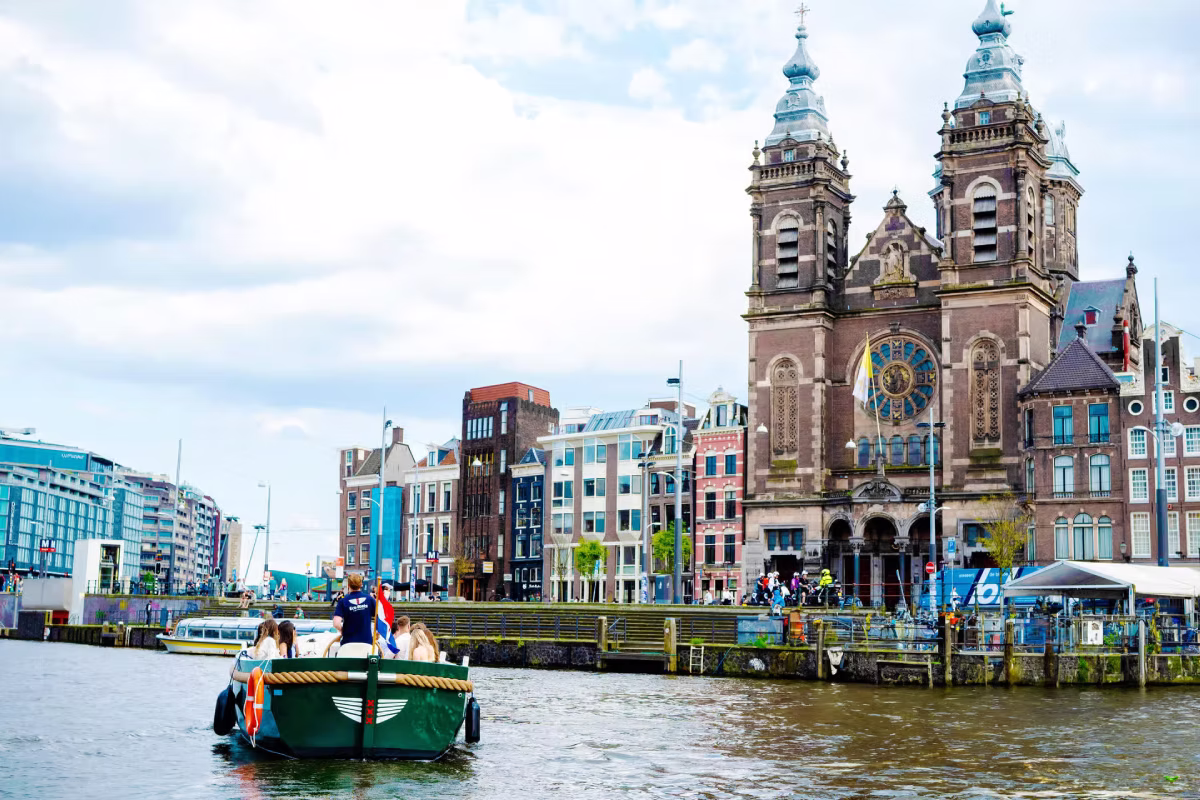 A canal cruise boat passes the Basilica of Saint Nicholas in Amsterdam.
