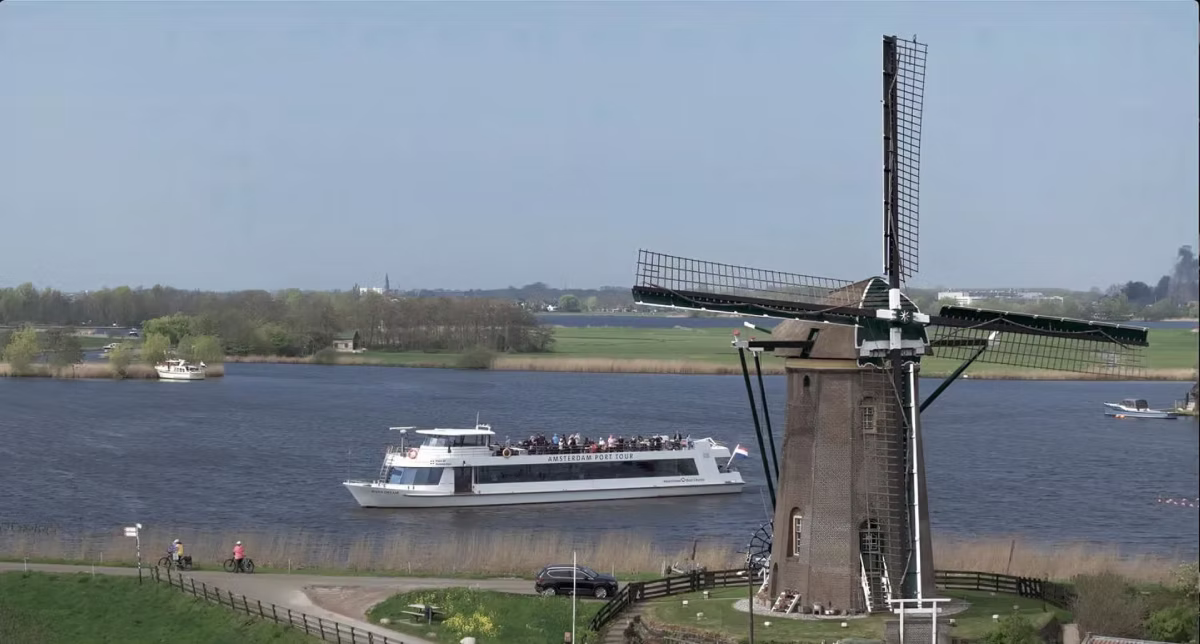 A boat tour passes a traditional windmill near Keukenhof.